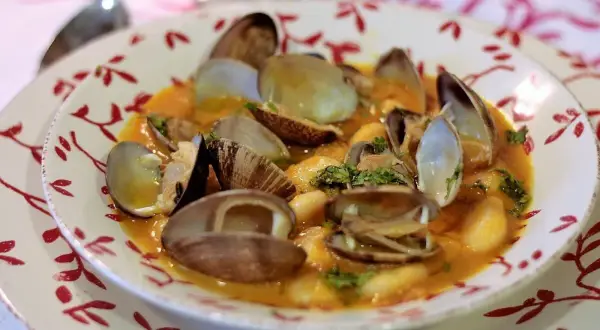 Plato de fabes con almejas, un guiso tradicional con judías blancas tiernas y almejas frescas en una salsa sabrosa.