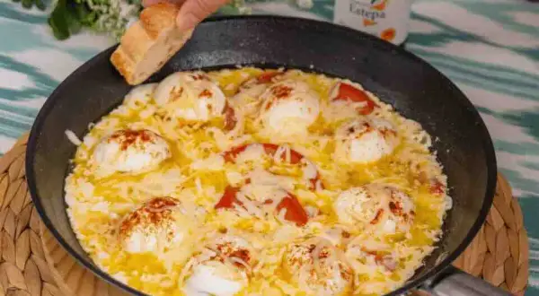 Huevos turcos recién hechos en sartén, con tomate y queso fundido, listos para mojar pan.