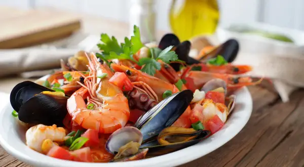 Un delicioso salpicón de marisco con gambas, mejillones, pulpo y almejas, adornado con tomate y perejil.