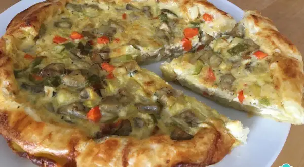Un delicioso quiche de verduras, con una masa dorada y un relleno cremoso de champiñones, calabacín y zanahoria.