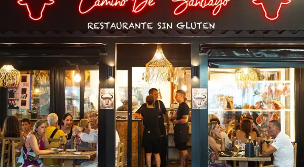 Restaurante "Camino de Santiago" en Peñíscola, con letrero de neón y comensales disfrutando de una comida.