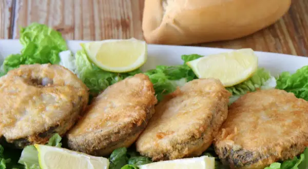 Crujiente merluza a la romana, servida sobre lechuga fresca y gajos de limón. Un plato perfecto para disfrutar.