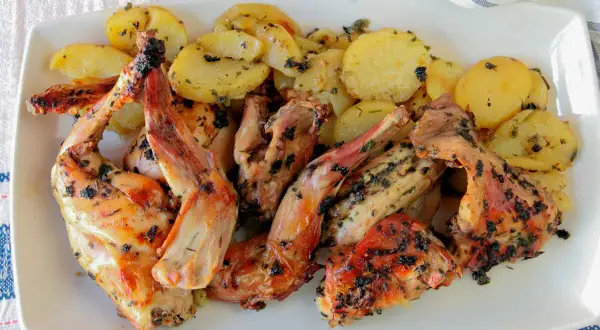 Delicioso conejo al horno con patatas doradas y hierbas aromáticas, listo para servir.