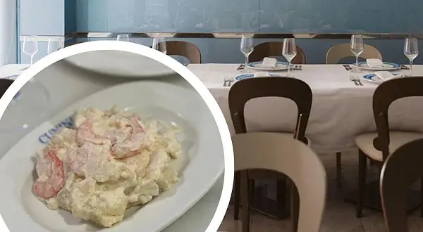 Deliciosa ensaladilla de gambas cremosa, servida en un plato blanco, lista para disfrutar en un restaurante con mesas puestas.