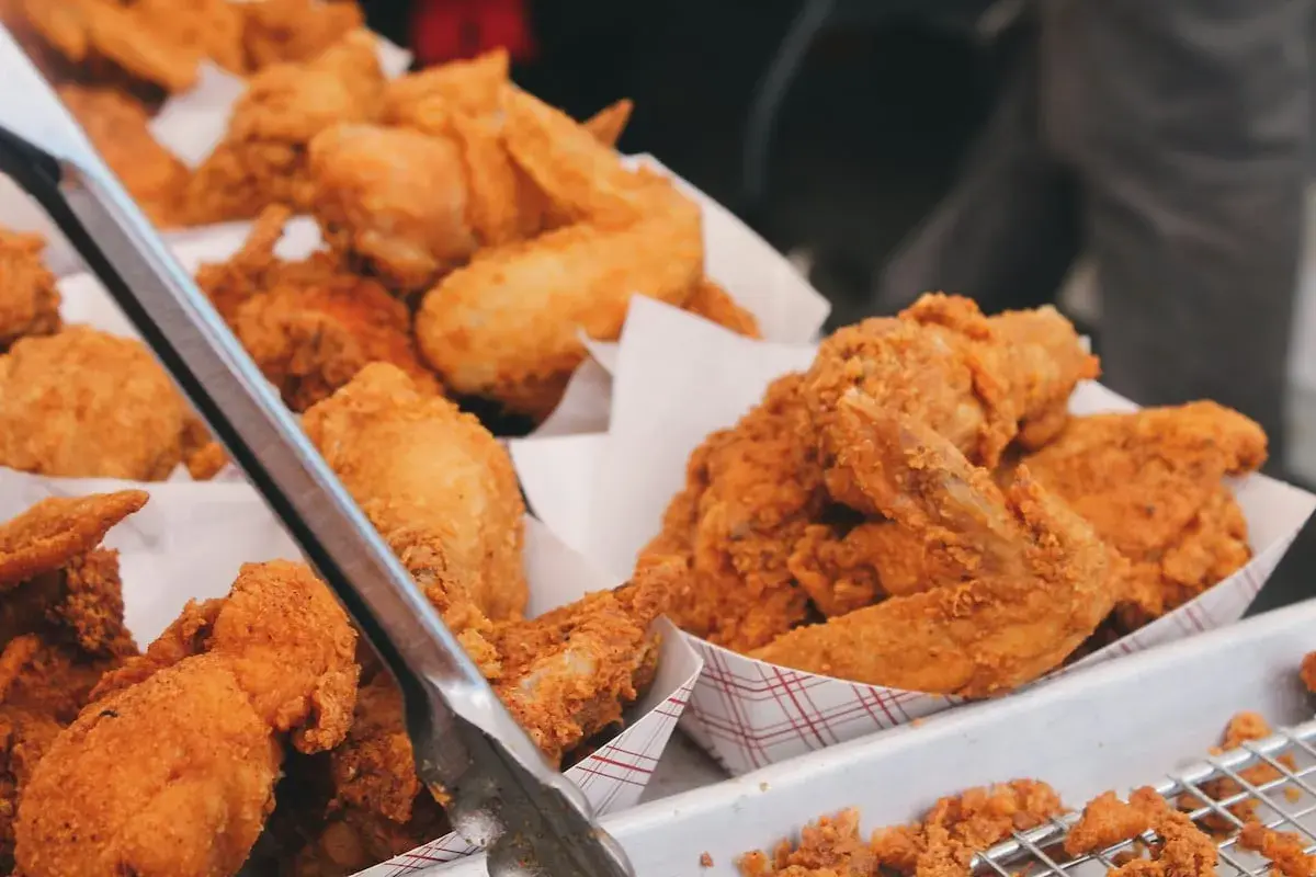 Unas bandejas llenas de crujiente pollo frito, listo para ser servido. Las piezas doradas y sabrosas invitan a disfrutar de este clásico.