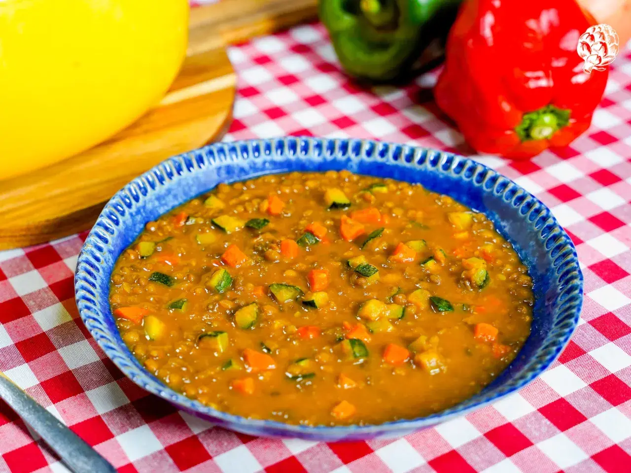 Un plato azul con un guiso de lentejas, zanahoria y calabacín. Una idea deliciosa de como hacer lentejas.