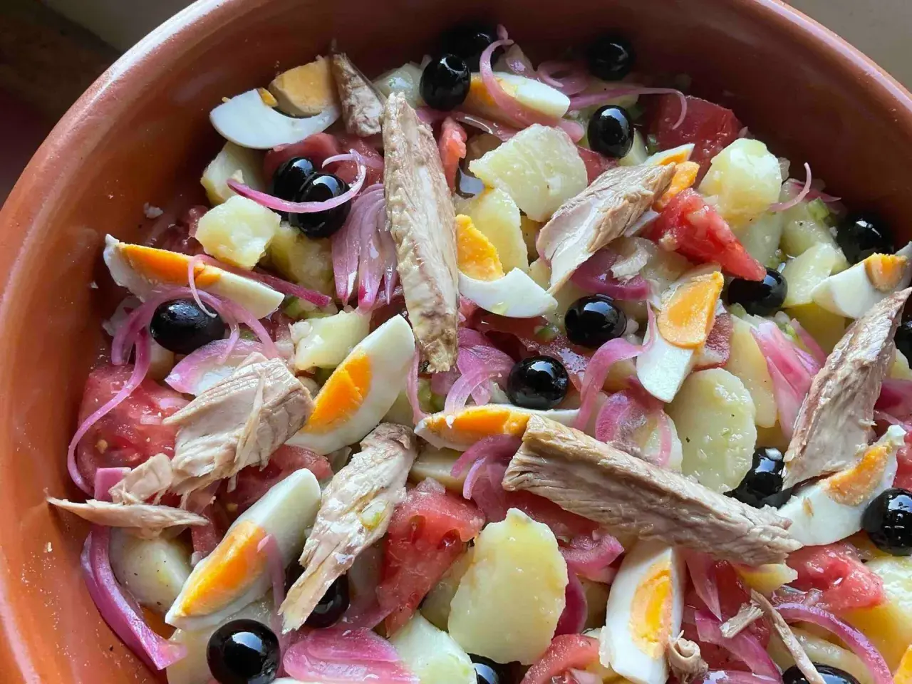 Deliciosa ensalada campera con patatas, huevo duro, atún, aceitunas negras y cebolla morada. ¡Un plato fresco y completo!