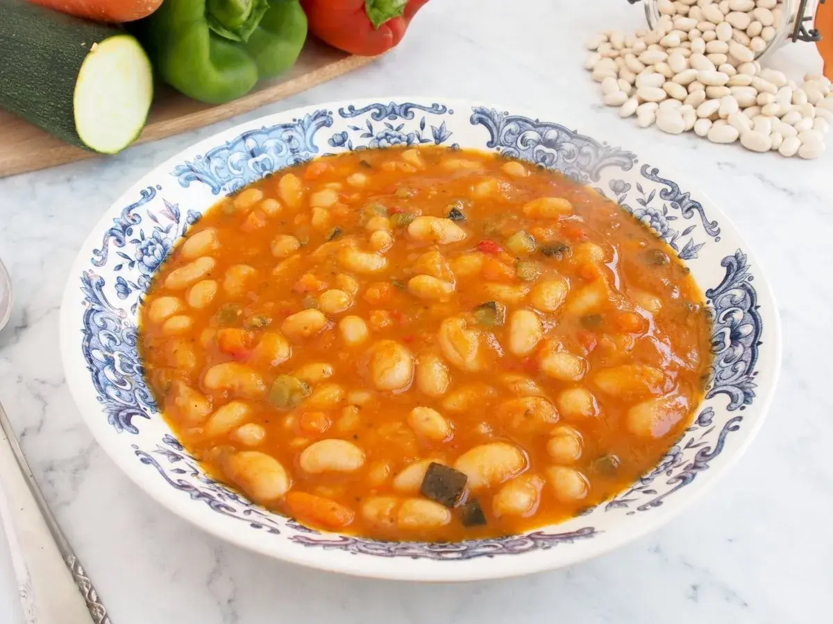 Plato de alubias blancas de bote con verduras en salsa de tomate. Un guiso casero y nutritivo, perfecto para tus recetas.