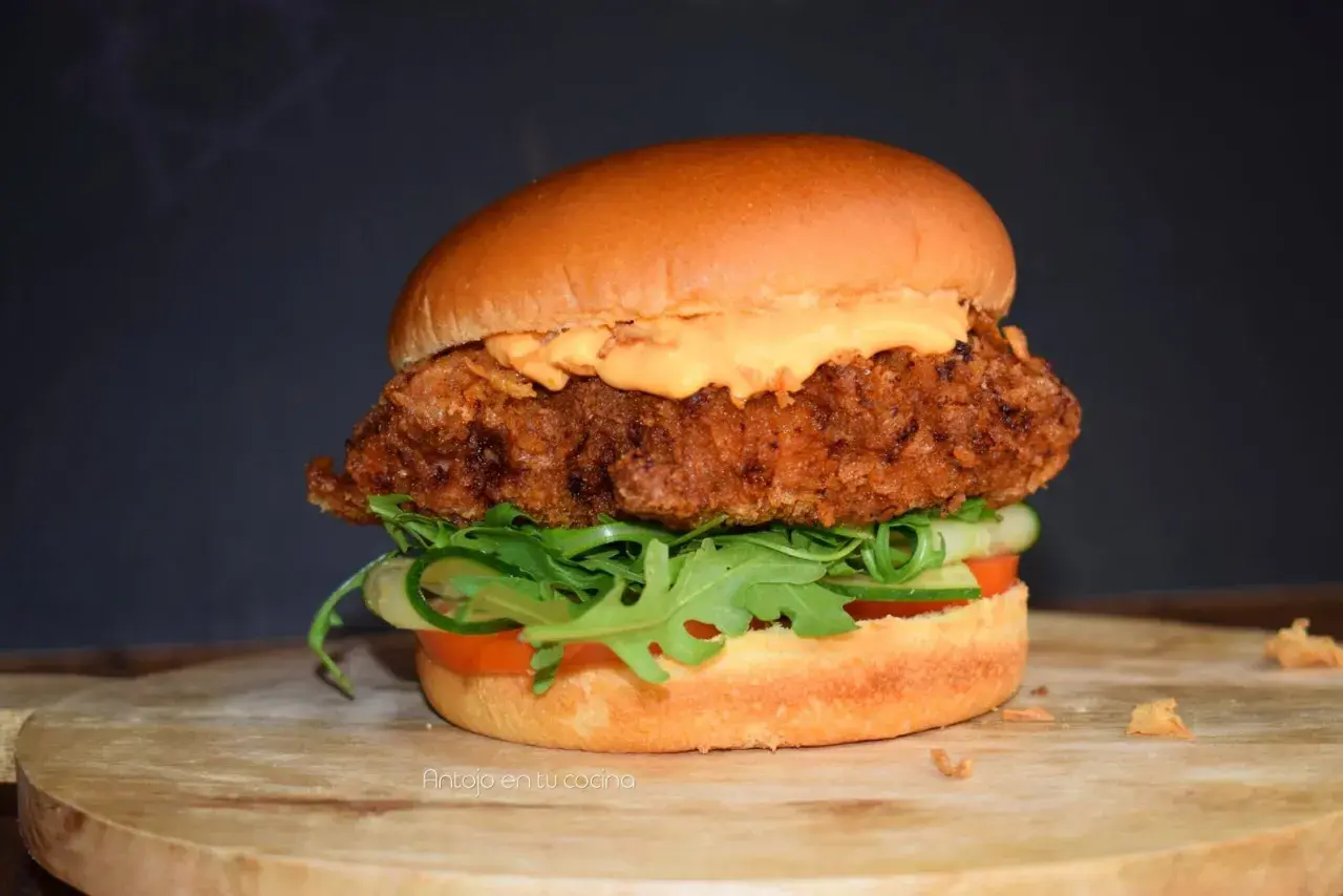 Deliciosa hamburguesa de pollo crujiente con lechuga, tomate y pepino, cubierta con una cremosa salsa.