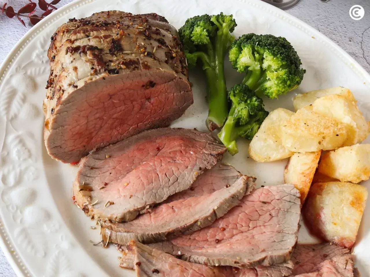 Jugoso roast beef cortado en rodajas, acompañado de brócoli al vapor y patatas asadas crujientes. Un festín para los sentidos.