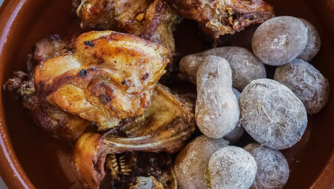Delicioso conejo al ajillo servido con papas arrugadas cubiertas de sal.