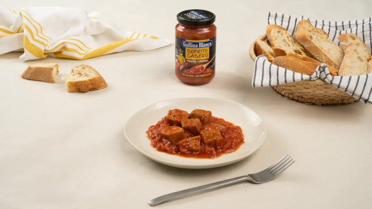 Sabroso atún con tomate en un plato, acompañado de pan y un sofrito casero de Gallina Blanca.