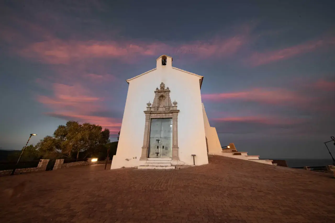 La ermita de Santa Lucía en Alcossebre se alza bajo un cielo crepuscular teñido de rosa y púrpura.