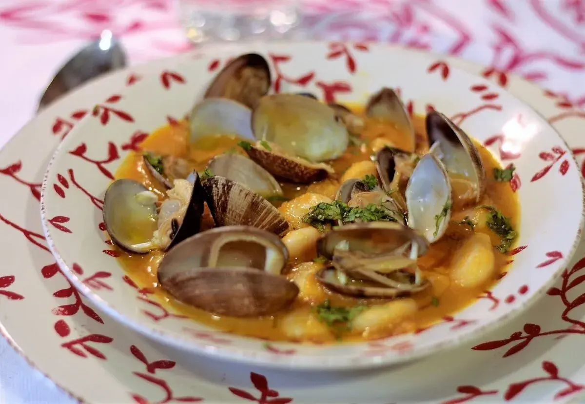 Plato de fabes con almejas, un guiso tradicional con judías blancas tiernas y almejas frescas en una salsa sabrosa.