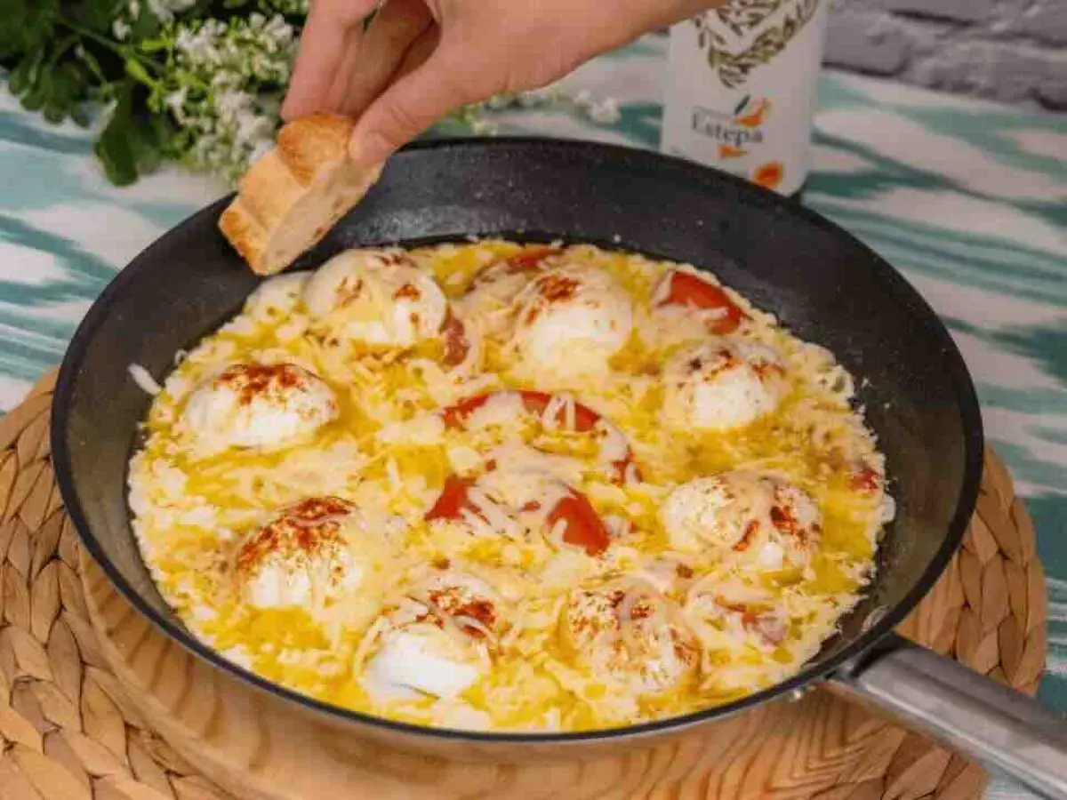 Huevos turcos recién hechos en sartén, con tomate y queso fundido, listos para mojar pan.