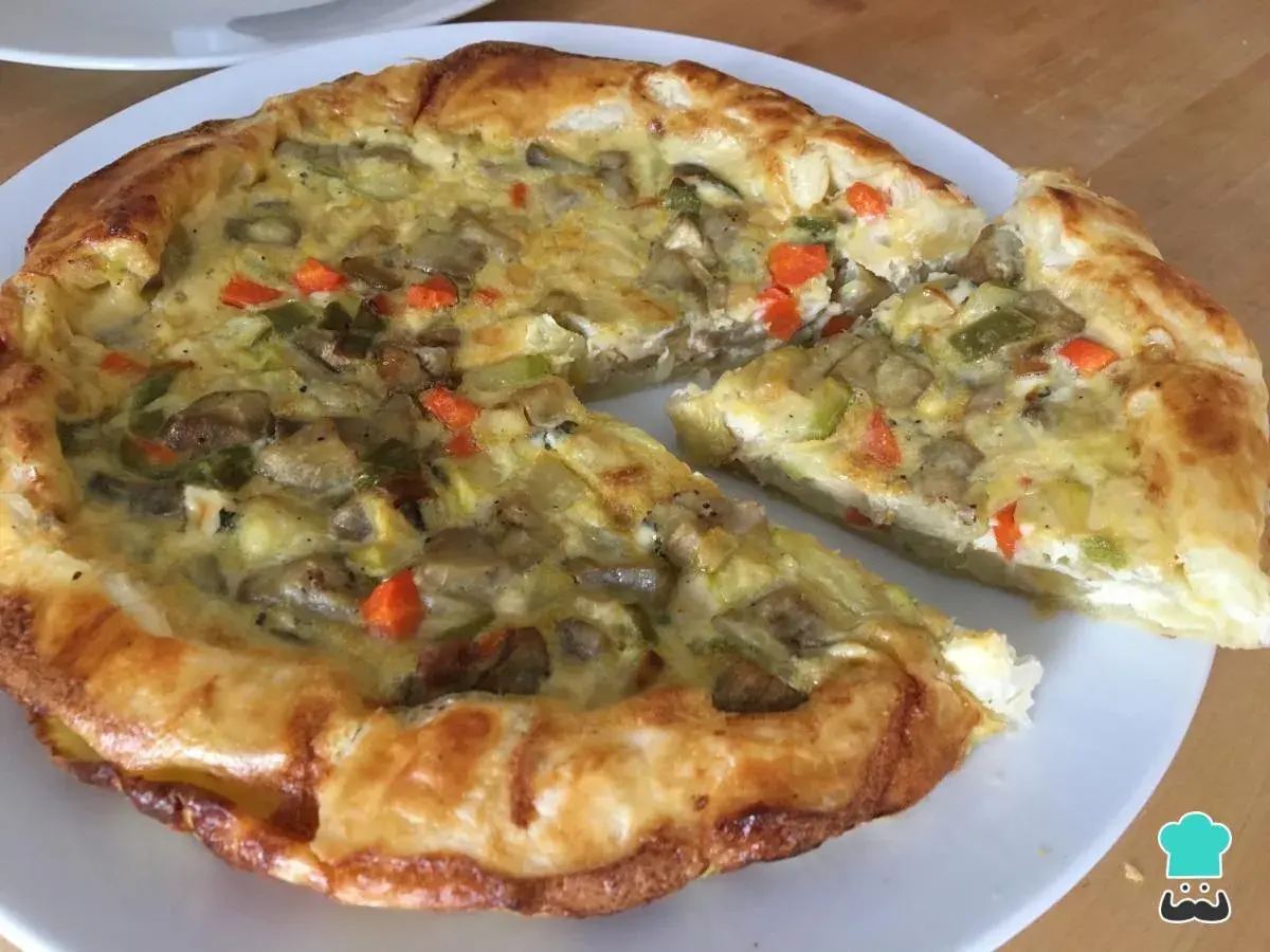 Un delicioso quiche de verduras, con una masa dorada y un relleno cremoso de champiñones, calabacín y zanahoria.
