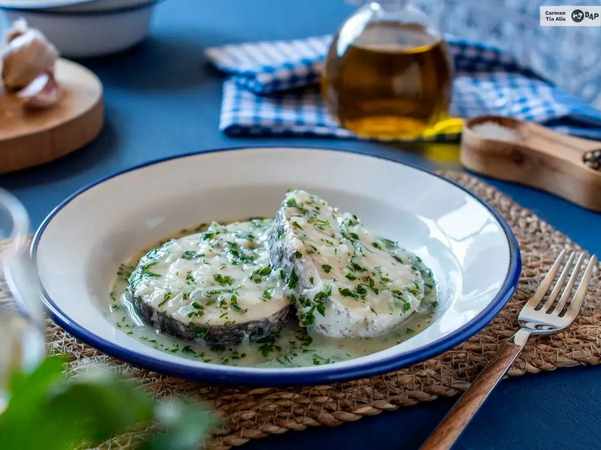 Dos rodajas de merluza en salsa verde, con perejil picado y ajo, listas para disfrutar.