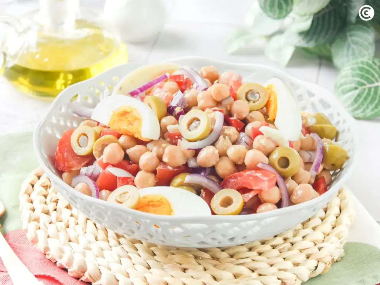 Ensalada de garbanzos con huevo duro, aceitunas, tomate y cebolla morada. Un plato fresco y nutritivo.