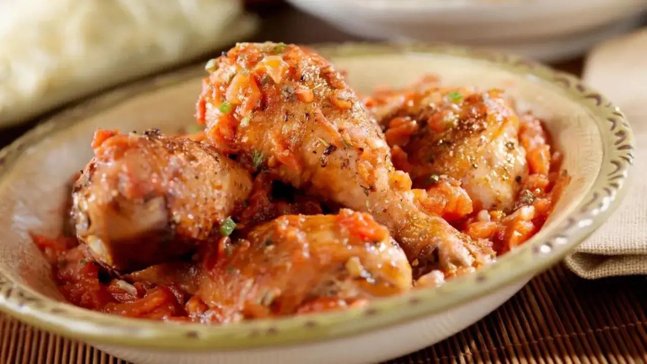 Sabroso pollo guisado en una salsa de tomate con hierbas, servido en un cuenco rústico.
