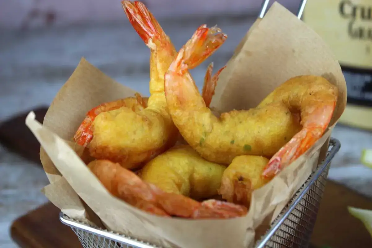 Crujientes gambas a la gabardina doradas y jugosas, servidas en una cesta met&aacute;lica forrada con papel de estraza.