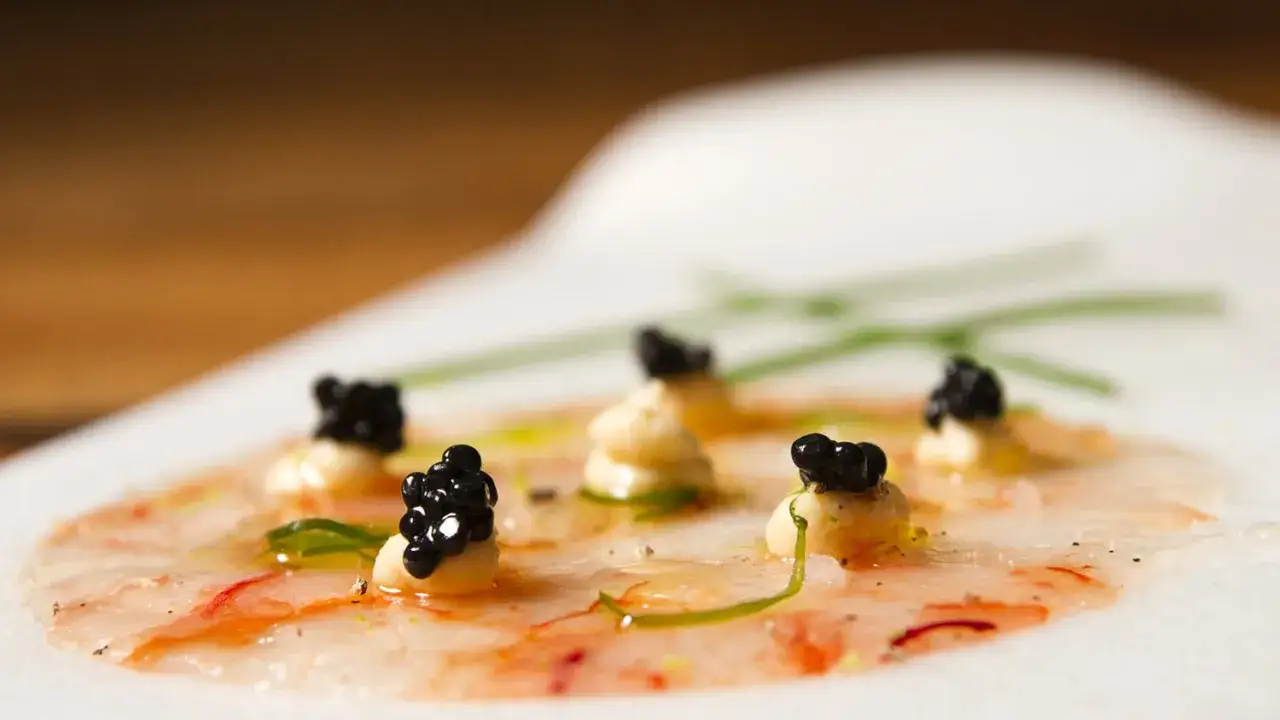 Delicado carpaccio de gambas con perlas de caviar negro y un toque de cebollino.