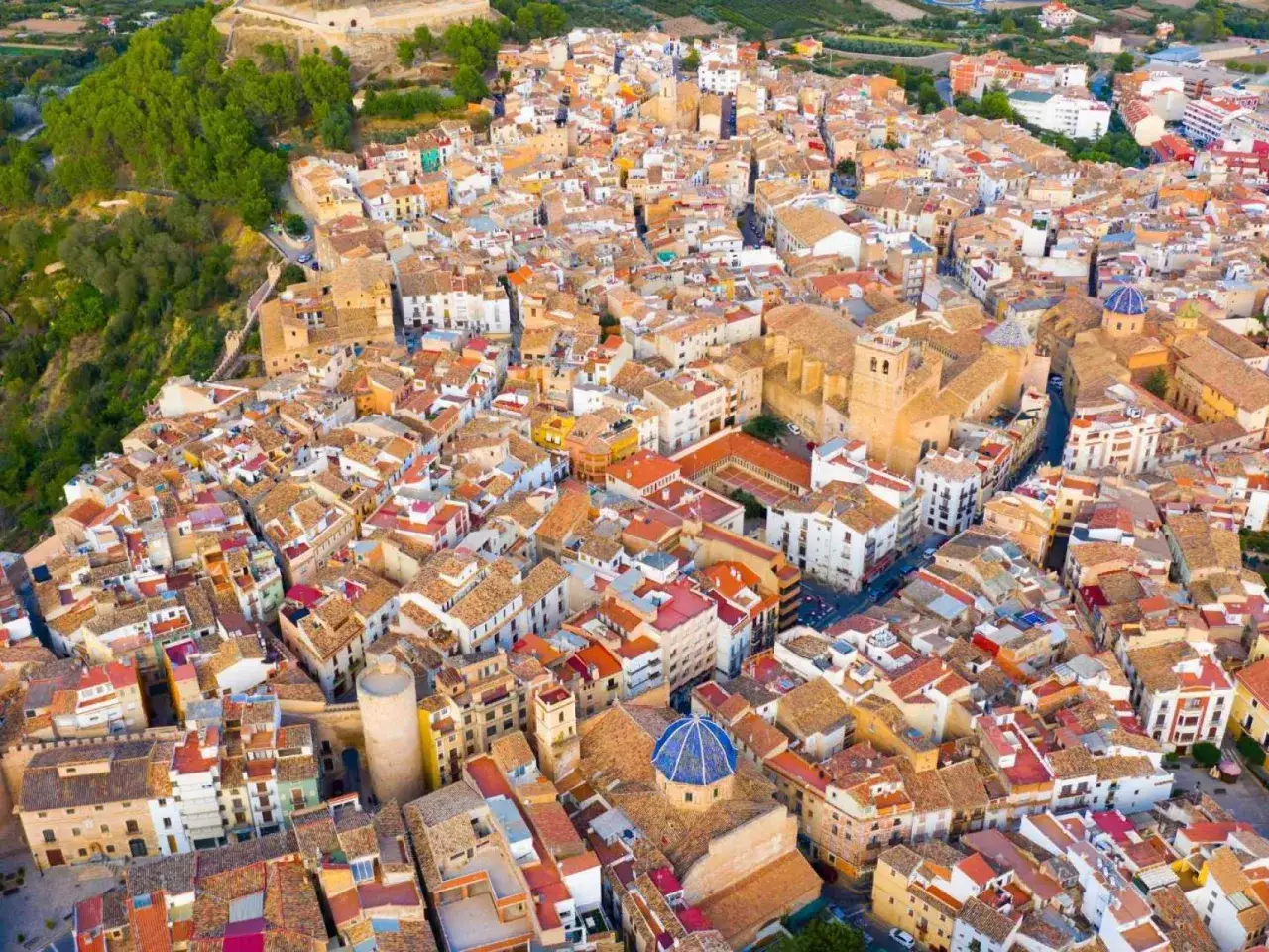 Vista a&eacute;rea de un pueblo con tejados naranjas y casas blancas, con una iglesia de c&uacute;pula azul. Un ejemplo de los pueblos bonitos cerca de Benicassim.