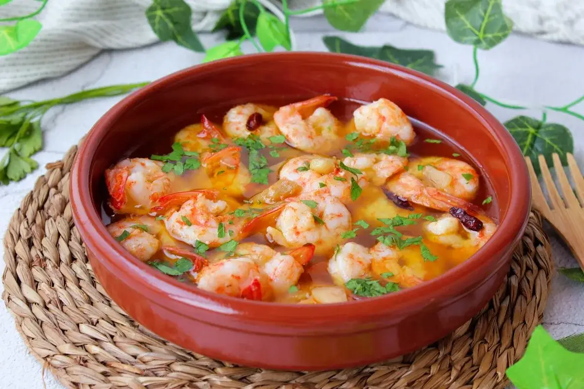 Gambones al ajillo burbujeantes en cazuela de barro, con perejil fresco picado y un toque de guindilla. &iexcl;Un placer para la vista y el paladar!