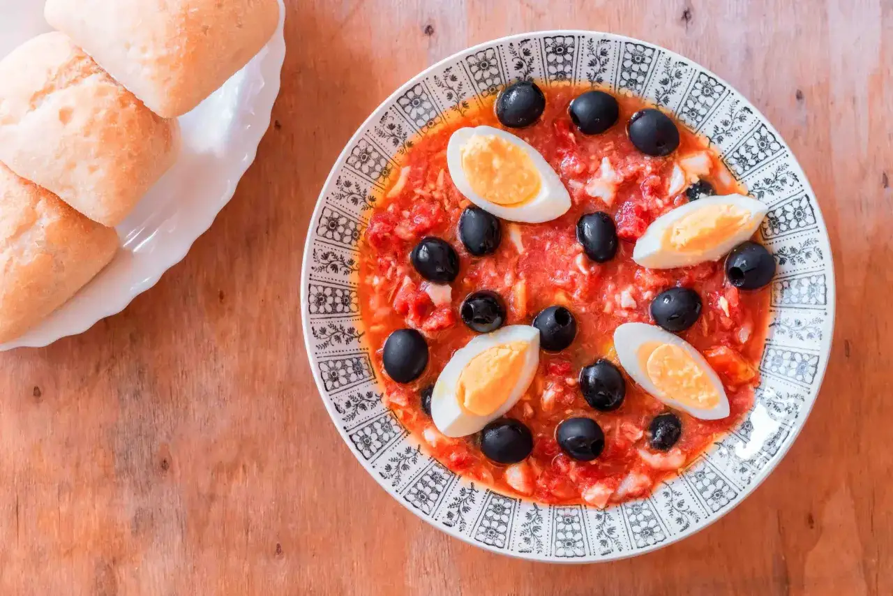 Ensalada murciana con huevo duro y aceitunas negras, acompa&ntilde;ada de panecillos.