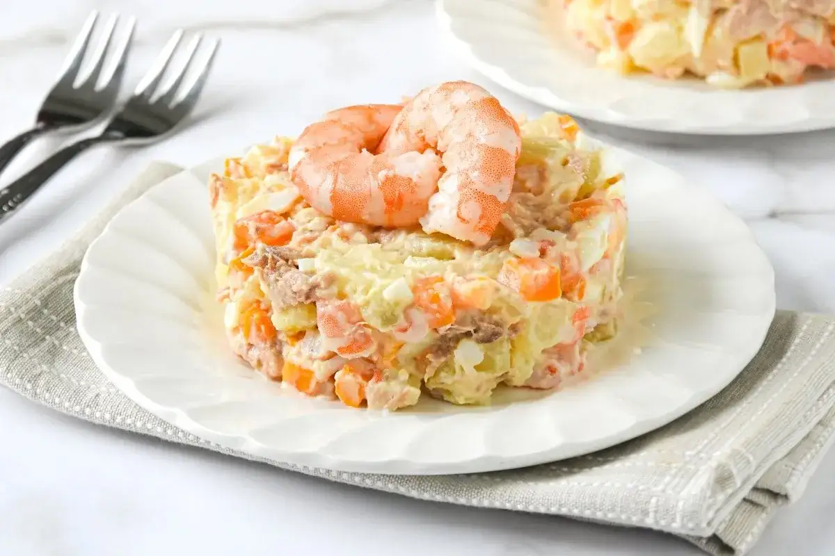 Deliciosa ensaladilla de gambas con patatas, zanahoria y huevo, coronada con dos gambas rojas.