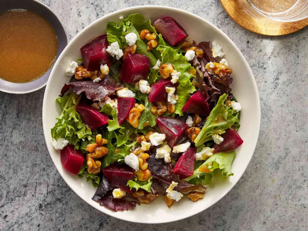 Deliciosa ensalada de remolacha con queso de cabra desmenuzado y nueces crujientes sobre una cama de lechugas mixtas.