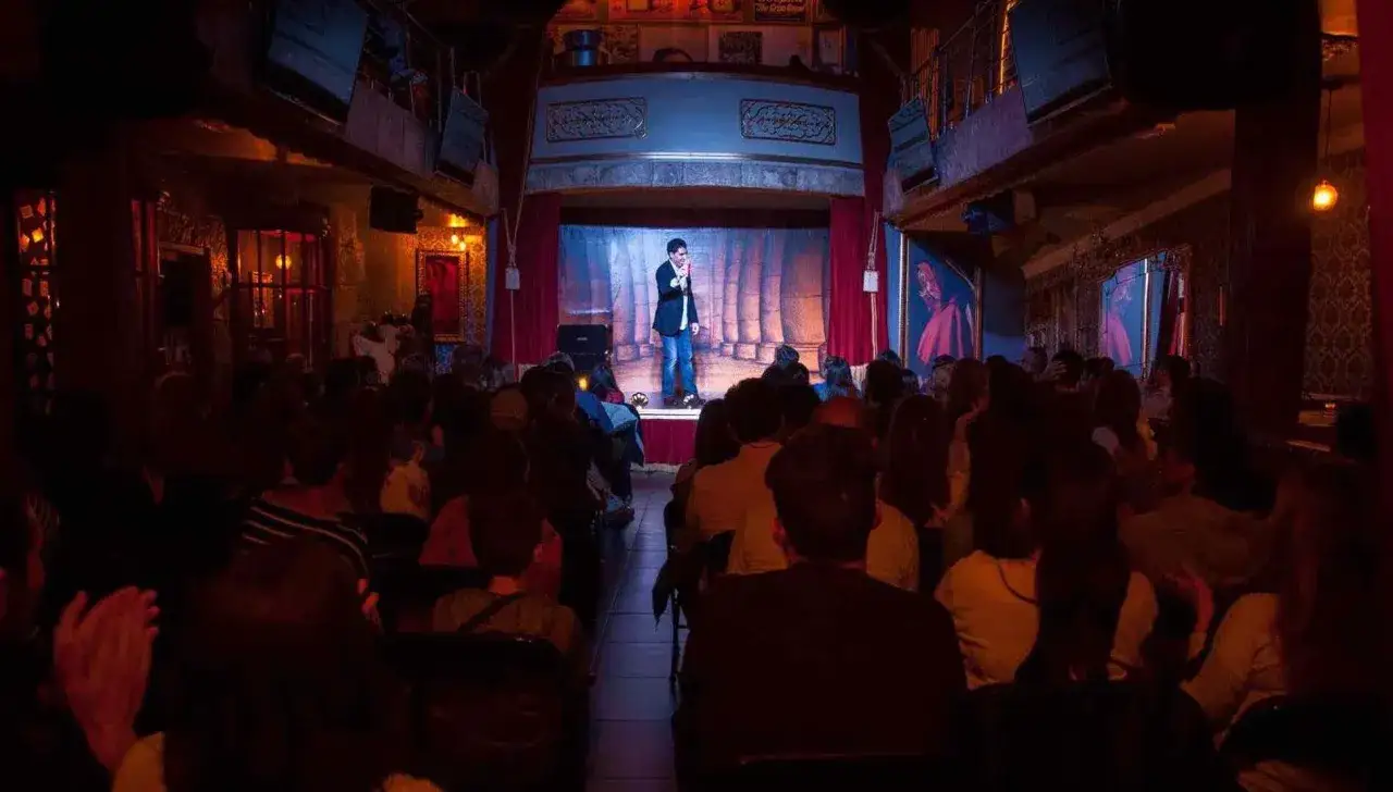 Un mago act&uacute;a en un escenario ante un p&uacute;blico en el magic museum Pe&ntilde;&iacute;scola. La sala tiene una decoraci&oacute;n teatral y oscura.