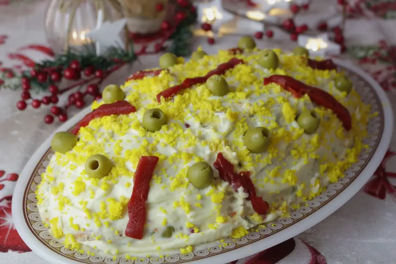 Ensaladilla rusa, la receta de la abuela, decorada con huevo rallado, aceitunas y pimientos. &iexcl;Un cl&aacute;sico navide&ntilde;o!