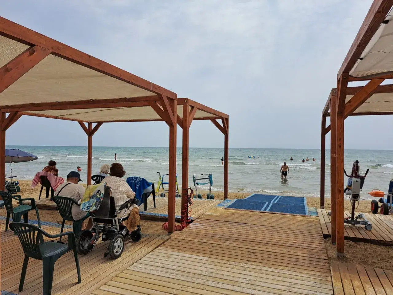 Personas disfrutan de la playa romana en Alcossebre, con rampas y accesos para sillas de ruedas.