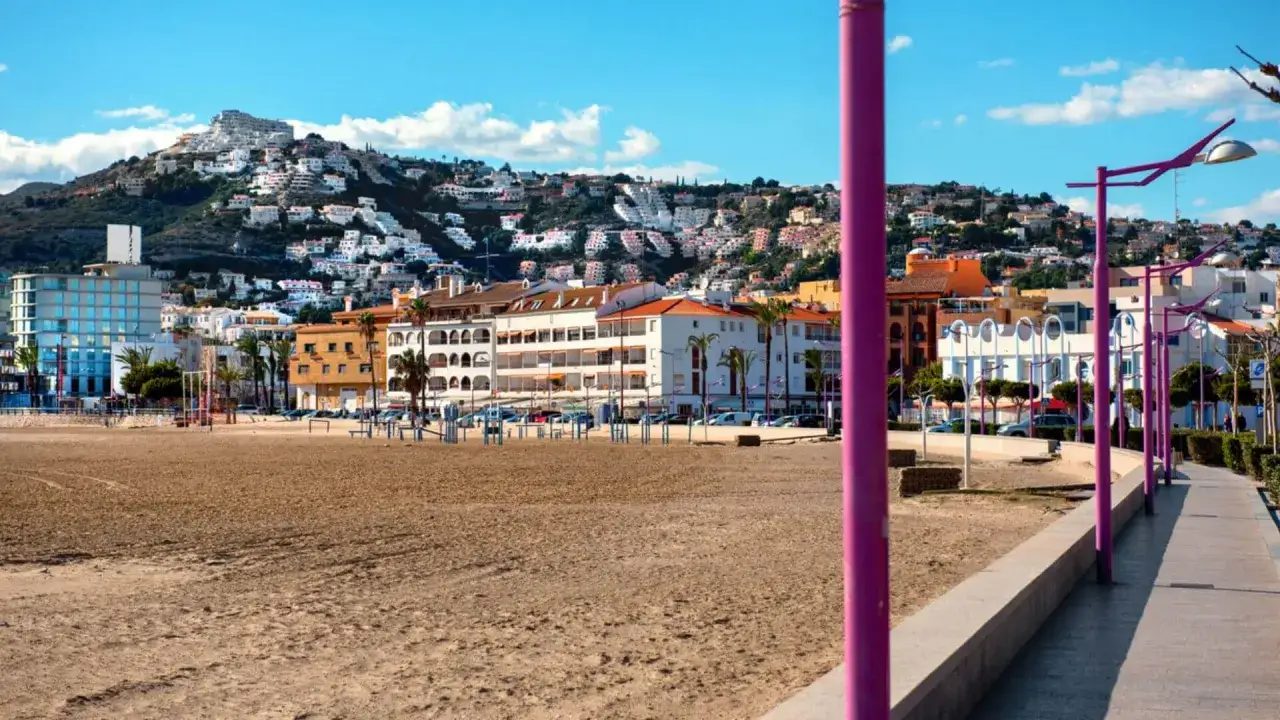 Playa y edificios en Pe&ntilde;&iacute;scola, con el castillo en la colina. El paseo mar&iacute;timo, con farolas moradas, invita a pasear.