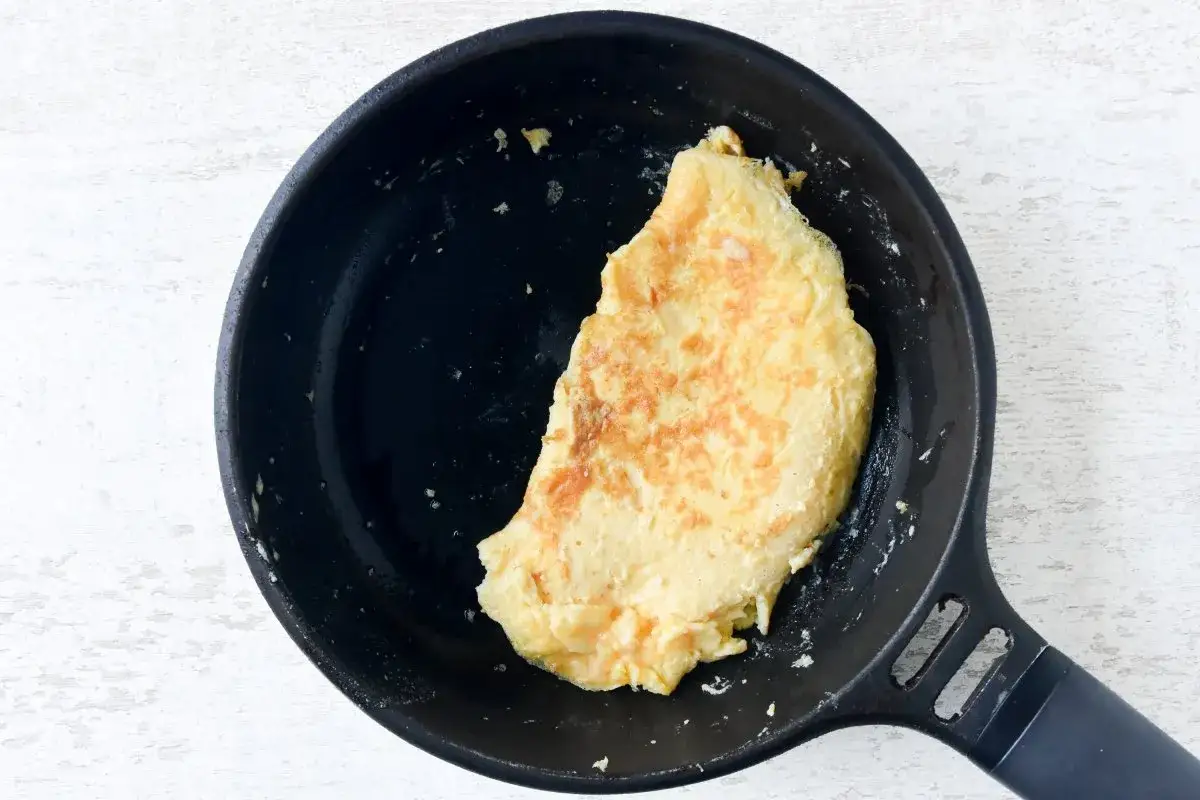 Tortilla francesa dorada en sart&eacute;n negra, lista para disfrutar.