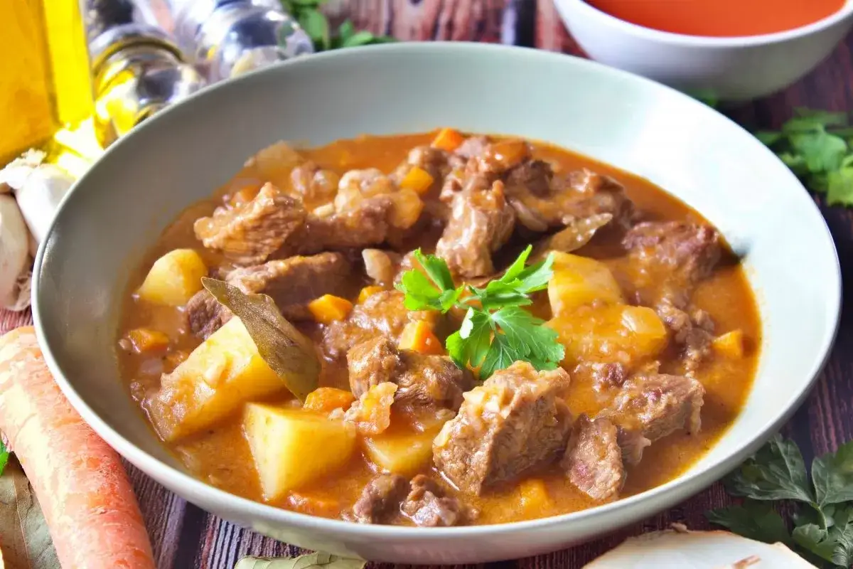Un reconfortante plato de carne guisada con patatas, zanahorias y hierbas frescas.