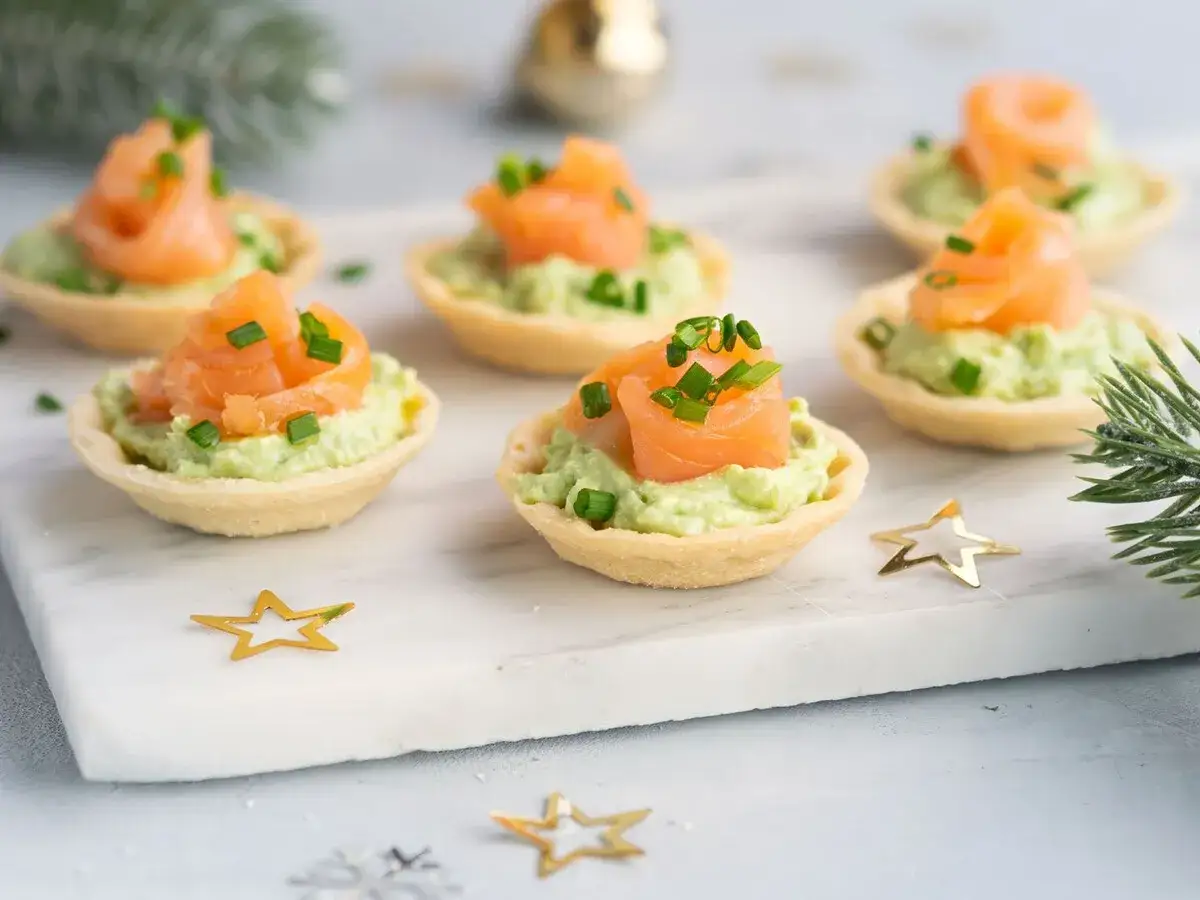 Aperitivos baratos para mucha gente: tartaletas con aguacate y salm&oacute;n ahumado, decoradas con cebollino.
