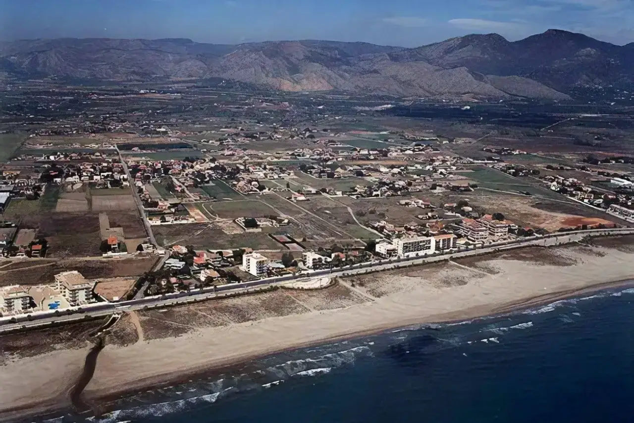 Vista a&eacute;rea de la playa del Serradal con urbanizaciones y monta&ntilde;as al fondo.
