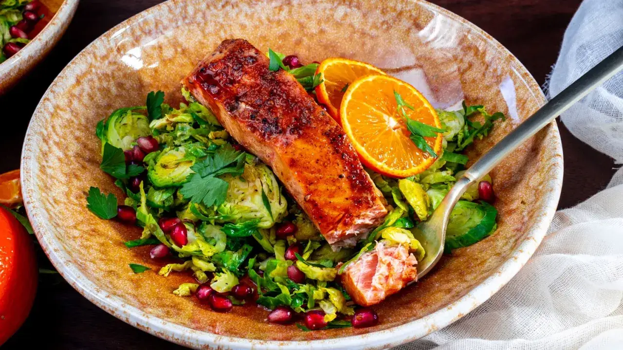 Salm&oacute;n a la naranja con ensalada de coles de Bruselas y granada. Un plato vibrante y delicioso.