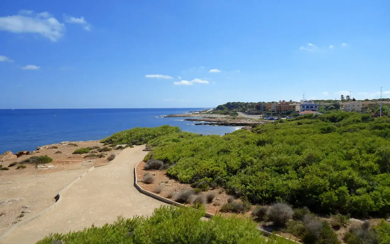 Senderos costeros y casas en Alcossebre, ideal para disfrutar con niños. Mar azul y vegetación exuberante.