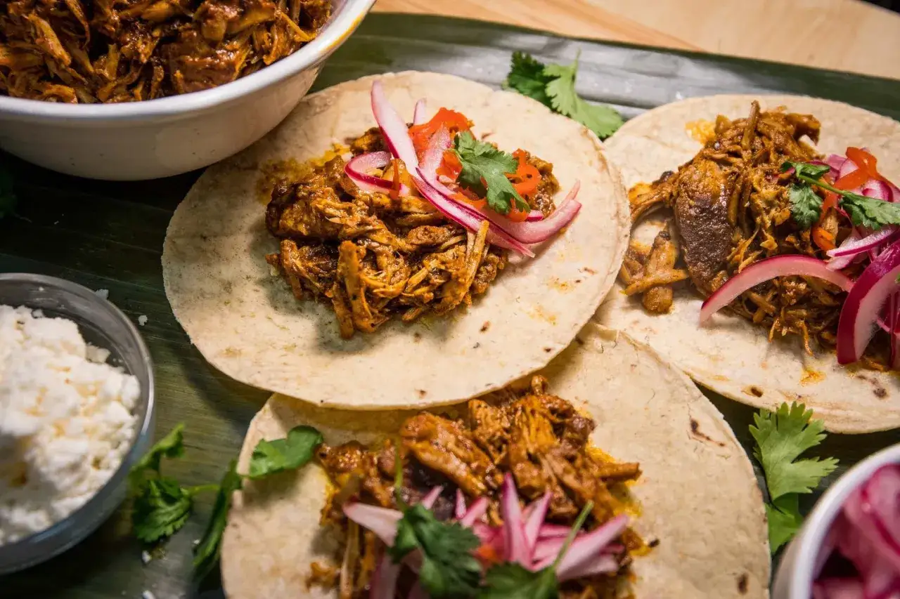 Tacos de cochinita pibil, con cebolla morada y cilantro. Un fest&iacute;n de sabor y tradici&oacute;n.