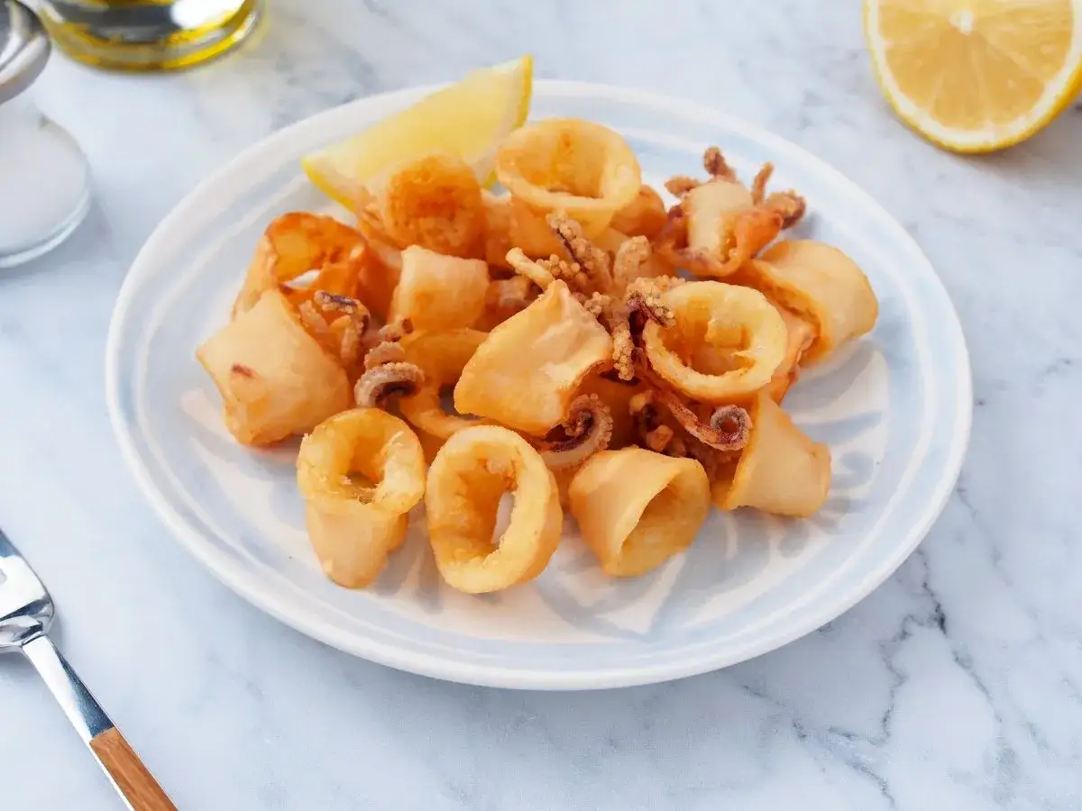 Calamares a la andaluza crujientes y dorados, servidos con un gajo de limón.