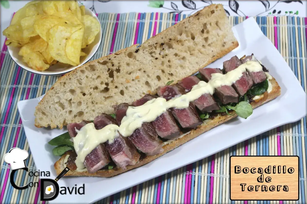 Bocadillo de ternera jugoso sobre pan rústico, con patatas fritas al lado. ¡Un manjar!