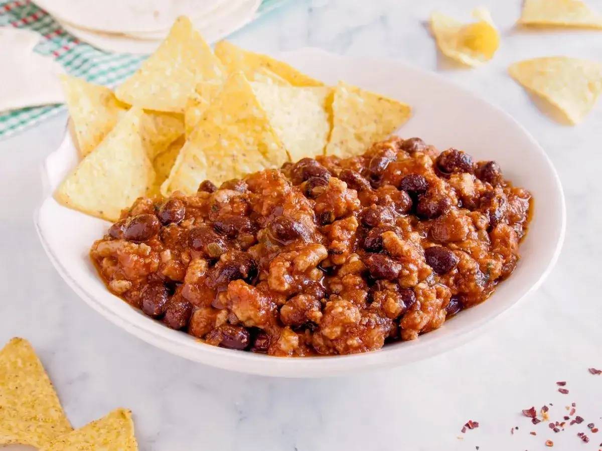 Un plato de chili con carne humeante, servido con totopos crujientes.