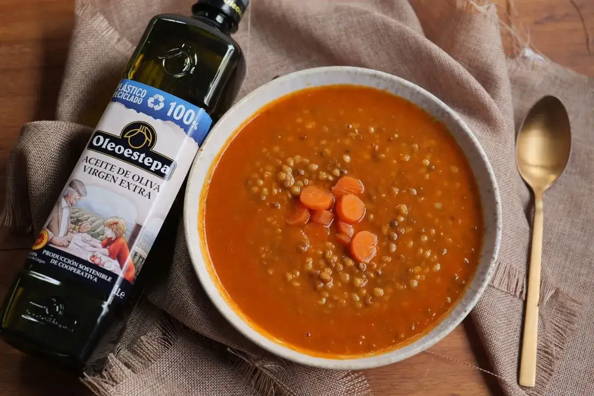 Un reconfortante plato de ensalada de lentejas con zanahoria, junto a una botella de aceite de oliva virgen extra Oleoestepa.