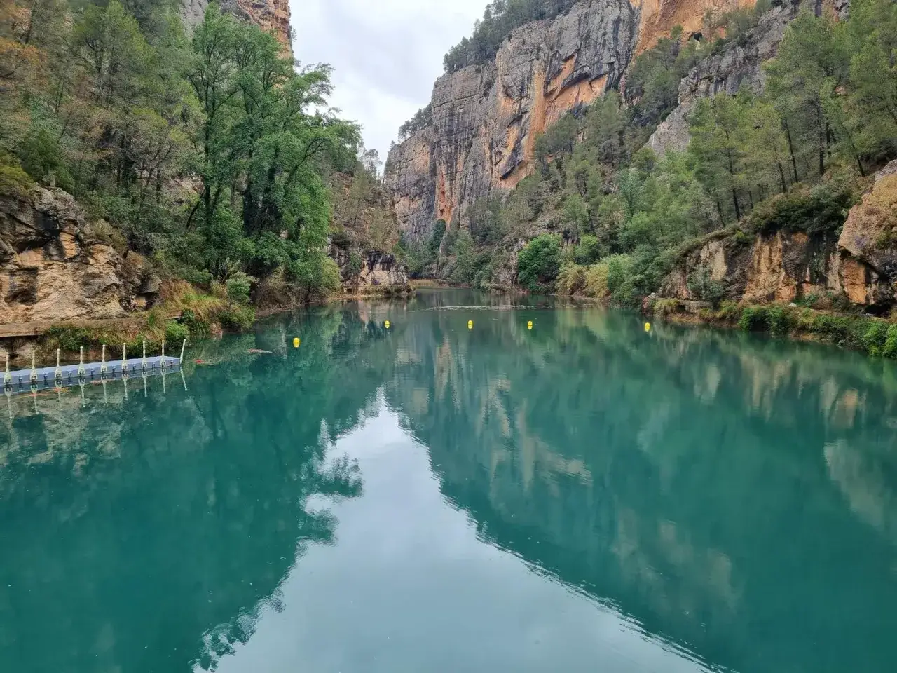 Aguas turquesas en la cueva negra de Montanejos, rodeada de acantilados y vegetaci&oacute;n.