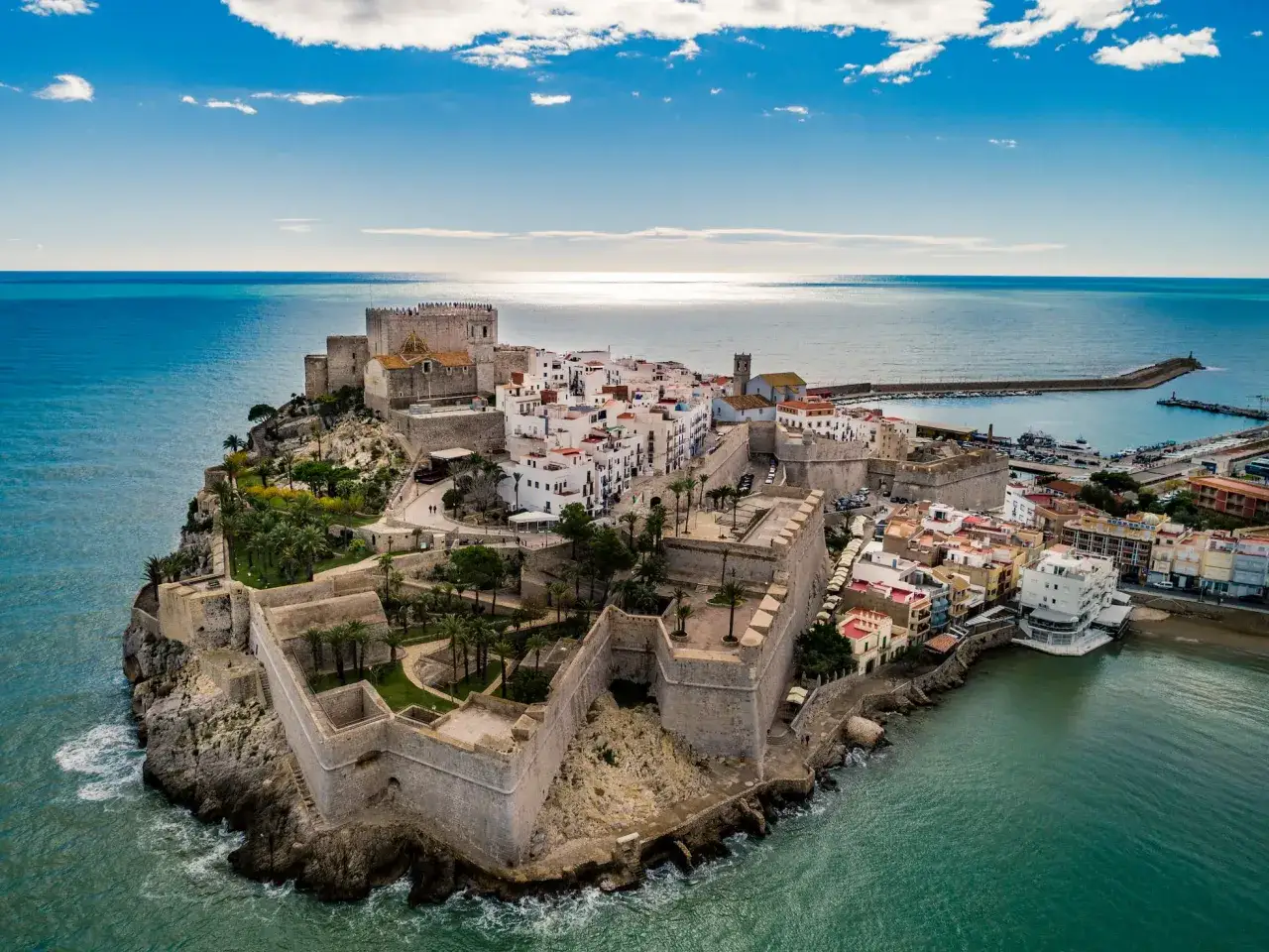 El imponente castillo de Pe&ntilde;&iacute;scola se alza sobre el mar Mediterr&aacute;neo, con sus murallas abrazando un pueblo blanco y un puerto pesquero.