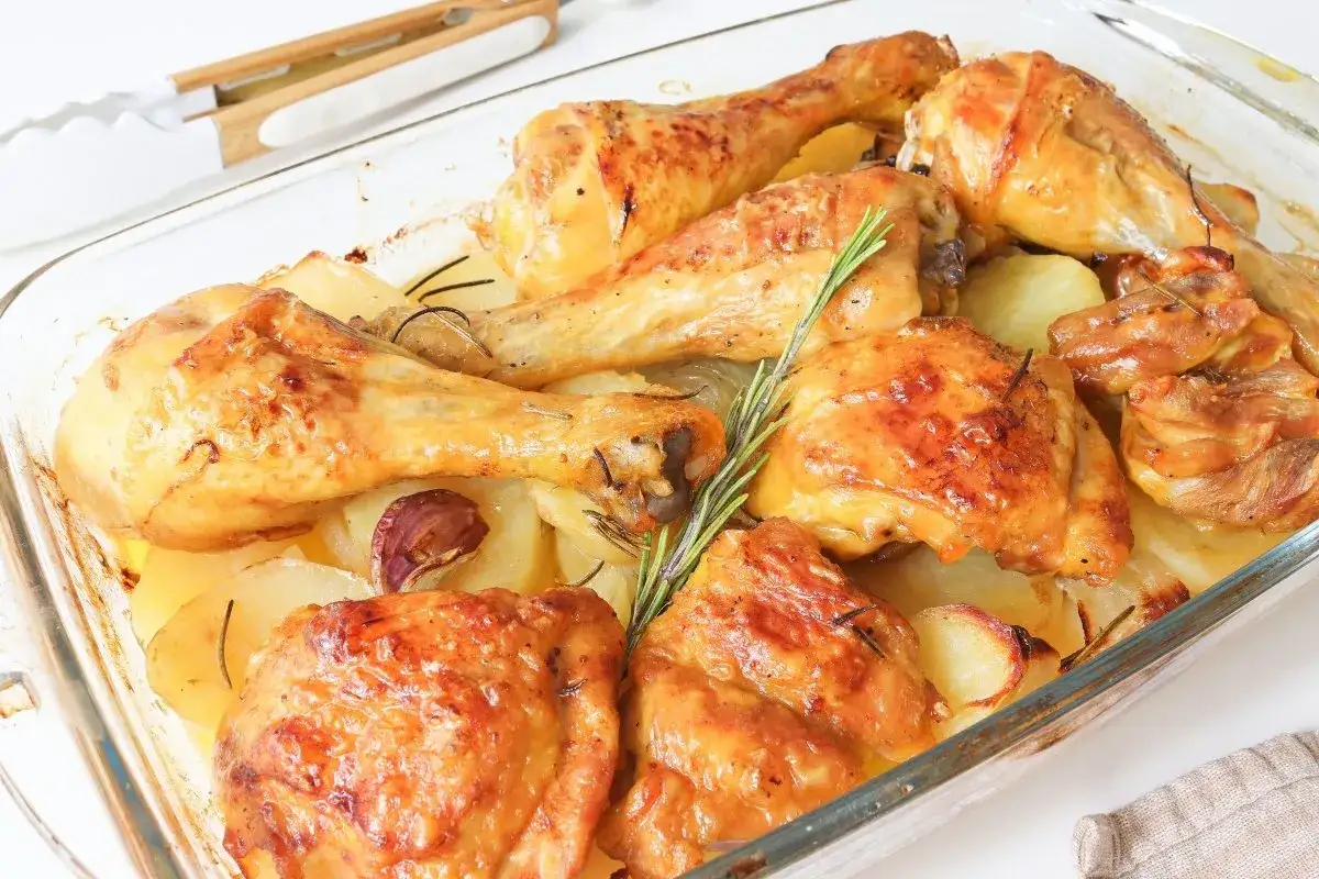 Pollo asado con patatas y romero en una bandeja de cristal. Un plato perfecto para tus recetas con pollo.