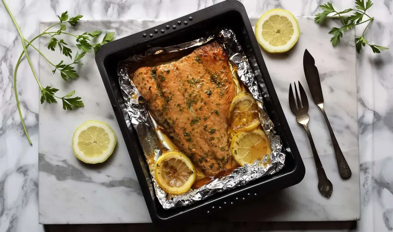 Salmón rosado al horno con limón y perejil en una bandeja, listo para servir.