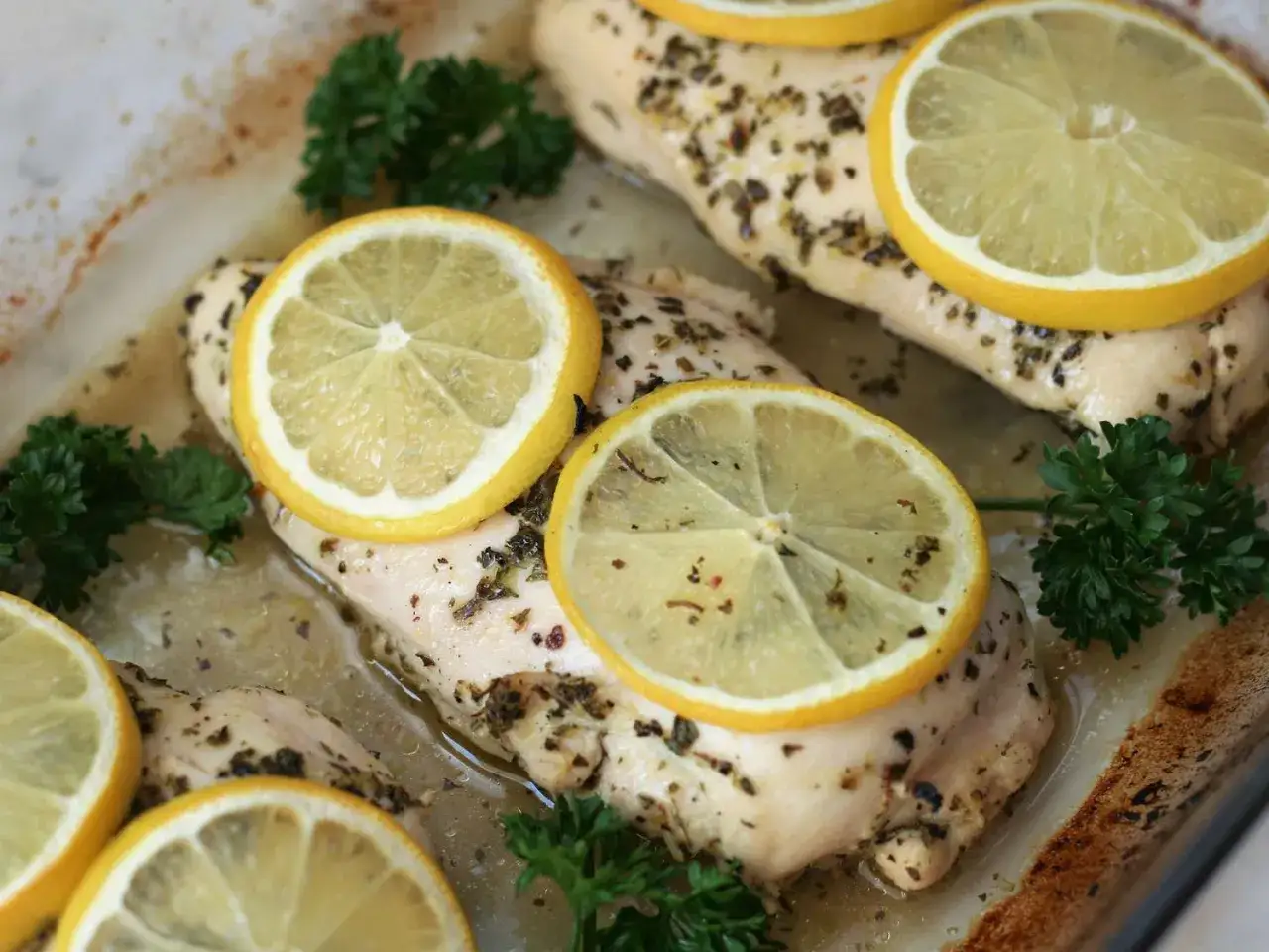 Pechugas de pollo al horno, jugosas y doradas, con rodajas de limón fresco y perejil. Un plato delicioso y saludable.